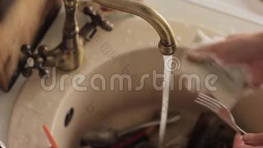 特写男士用手洗盘子，用水喷射从泡沫和洗涤剂中冲洗盘子